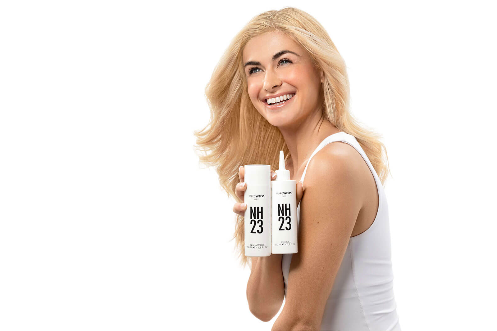 Blonde model holding NH23 shampoo and conditioner bottles